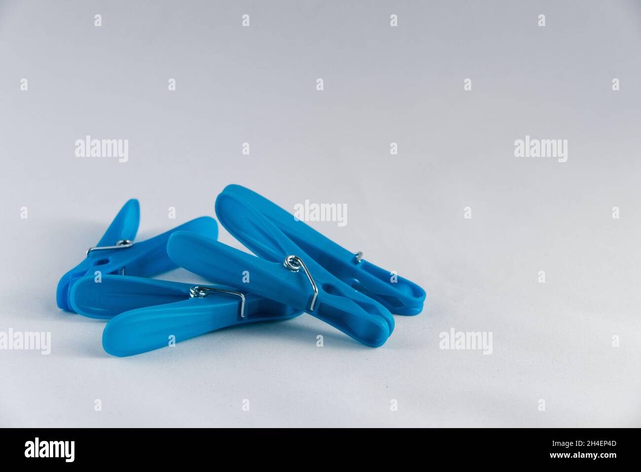Ein Haufen blauer Plastikklammern (Klamottenstifte), zufällig auf weißem Hintergrund gestapelt. Kopieren Sie den Speicherplatz nach oben rechts. Stockfoto