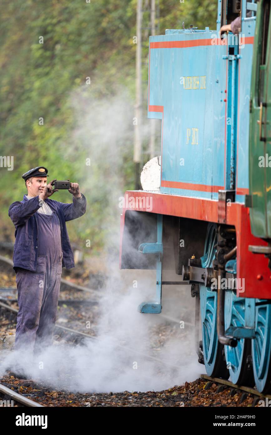 Ein Zugfahrer fotografiert mit seinem Telefon einen Dampfzug auf der Watercress Line Mid-Hants Railway, Alresford, Großbritannien Stockfoto