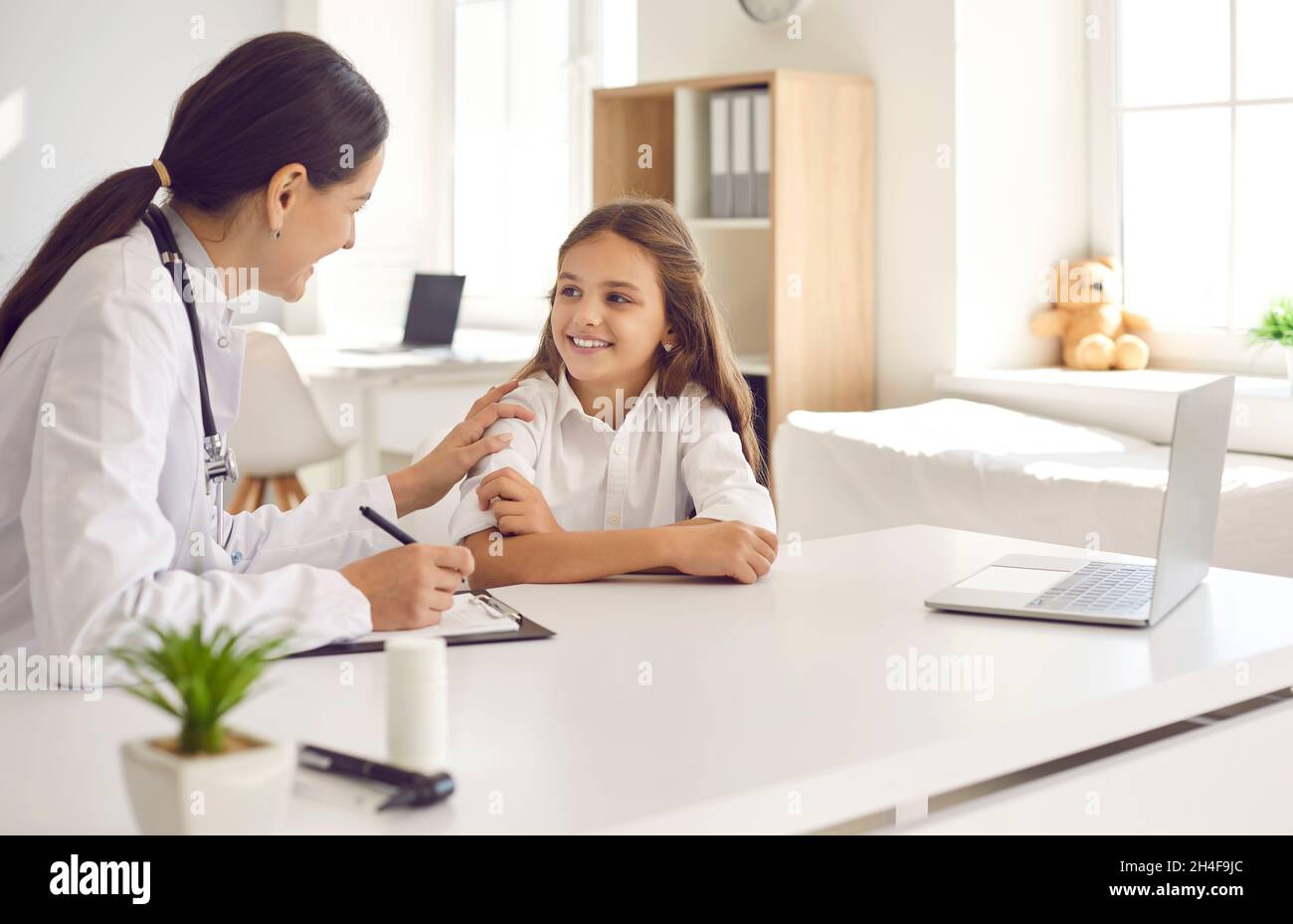 Freundliche und fürsorgliche Ärztin ermutigt kleine Mädchen vor einer ärztlichen Untersuchung. Stockfoto