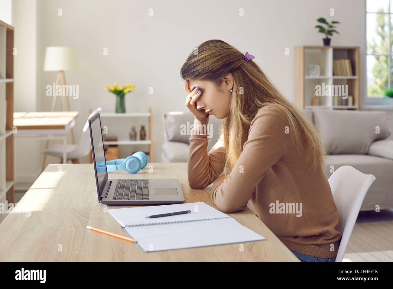 Gelangweilt frustrierte Studentin, die es leid ist, zu studieren, am Laptop zu arbeiten oder zu Hause zu sitzen. Stockfoto