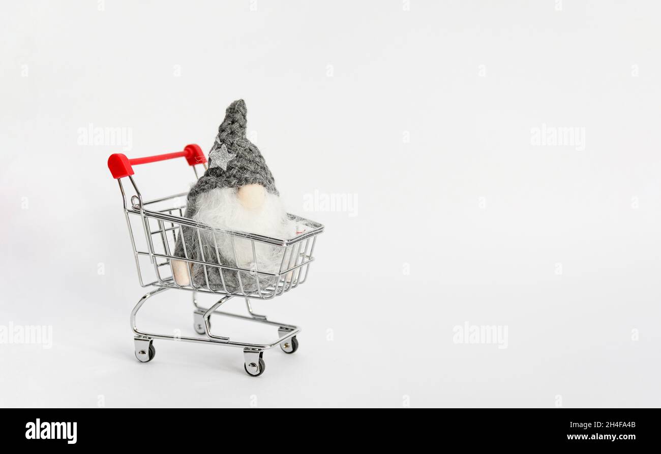 Spielzeug-Gnom im Mini-Einkaufswagen auf weißem Hintergrund mit Kopierfläche Stockfoto