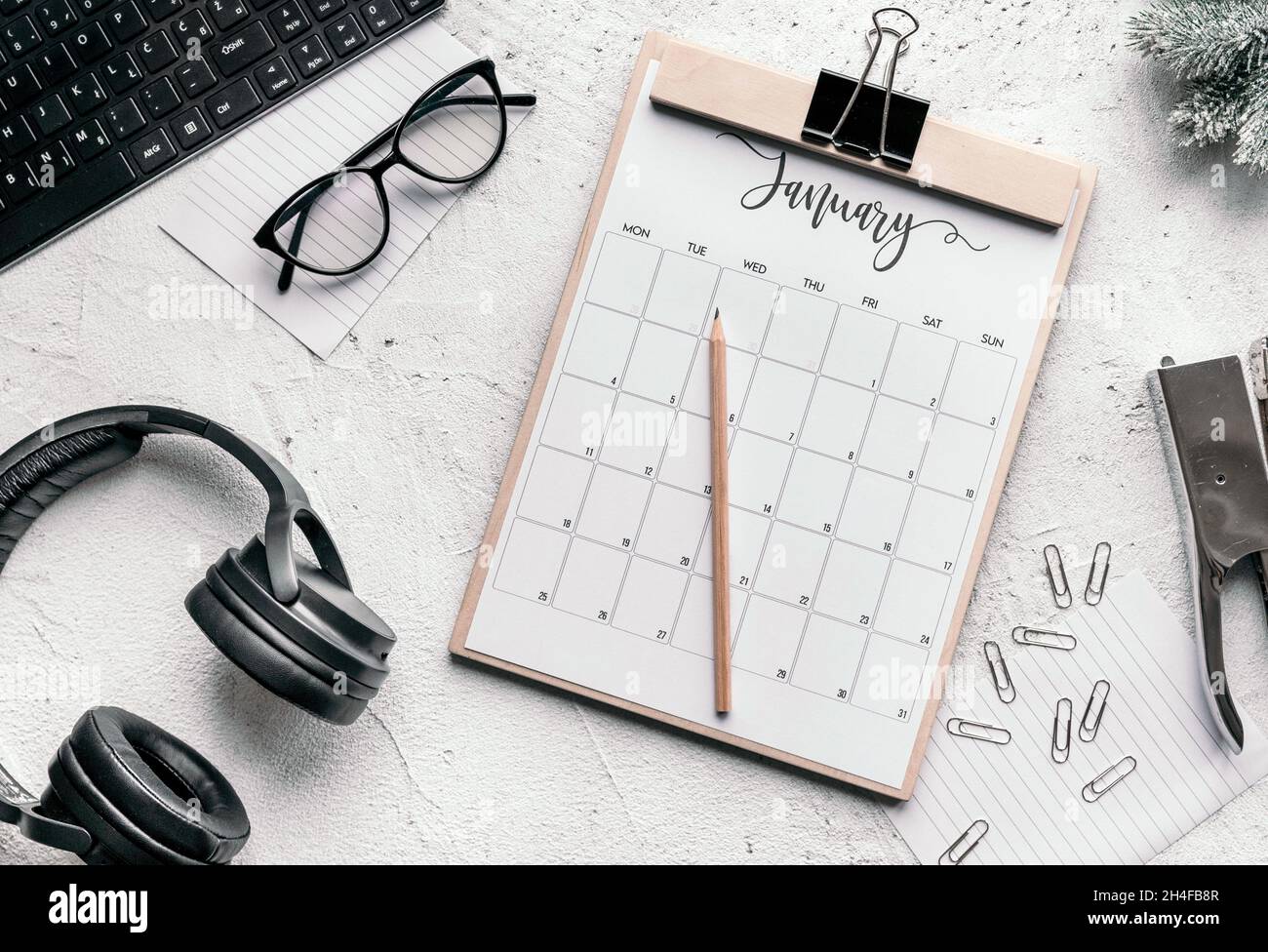 Januar Kalender flach lag. Draufsicht des Januarkalenders auf der Tabelle. Mobiltelefon mit Flip-Clock auf dem Bildschirm über dem Kalender auf hellem Hintergrund. Stockfoto