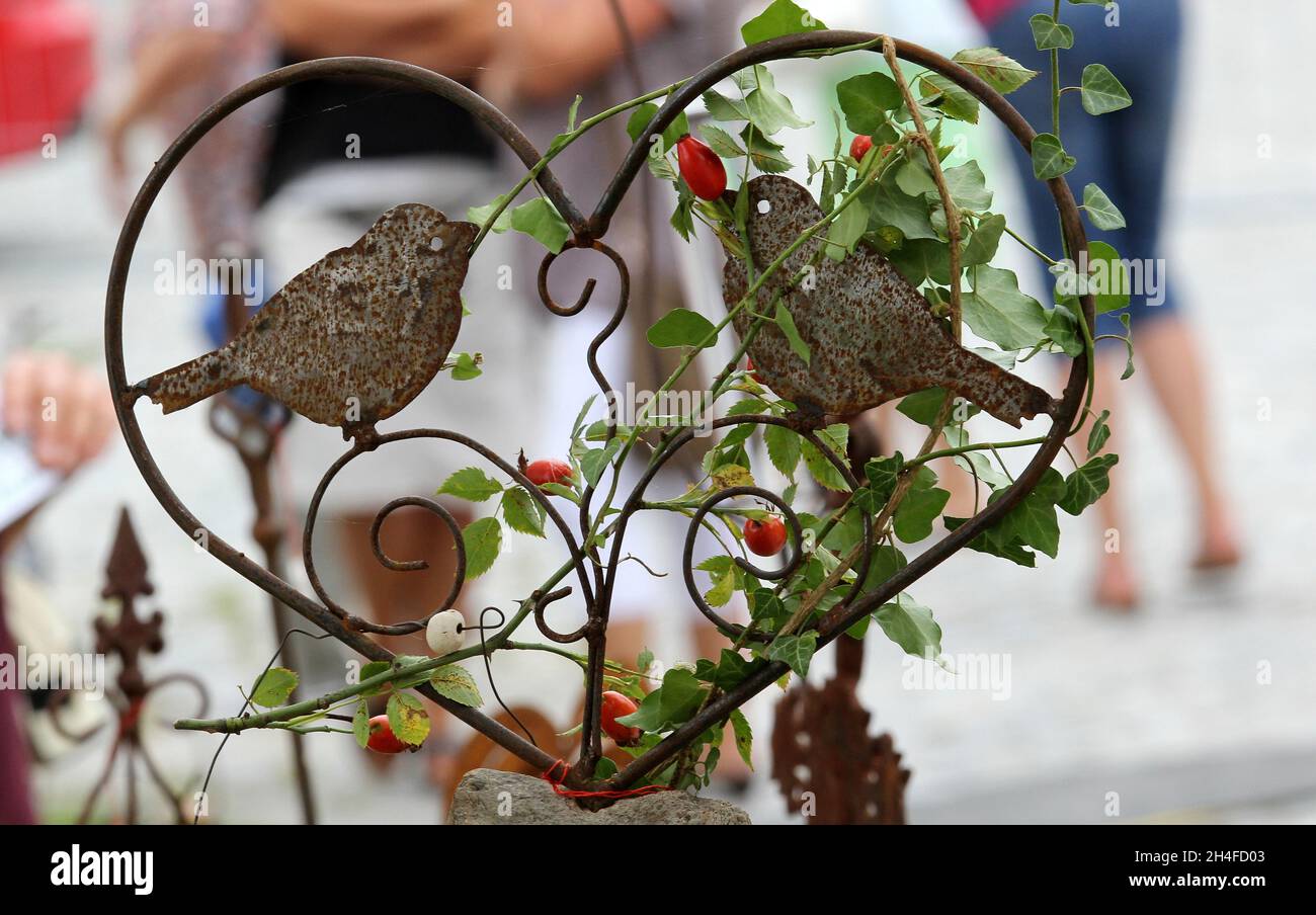 Nahaufnahme eines alten, rostig verwitterten, grungigen, herzförmigen Ornaments aus Eisen mit Vögeln im Freien Stockfoto