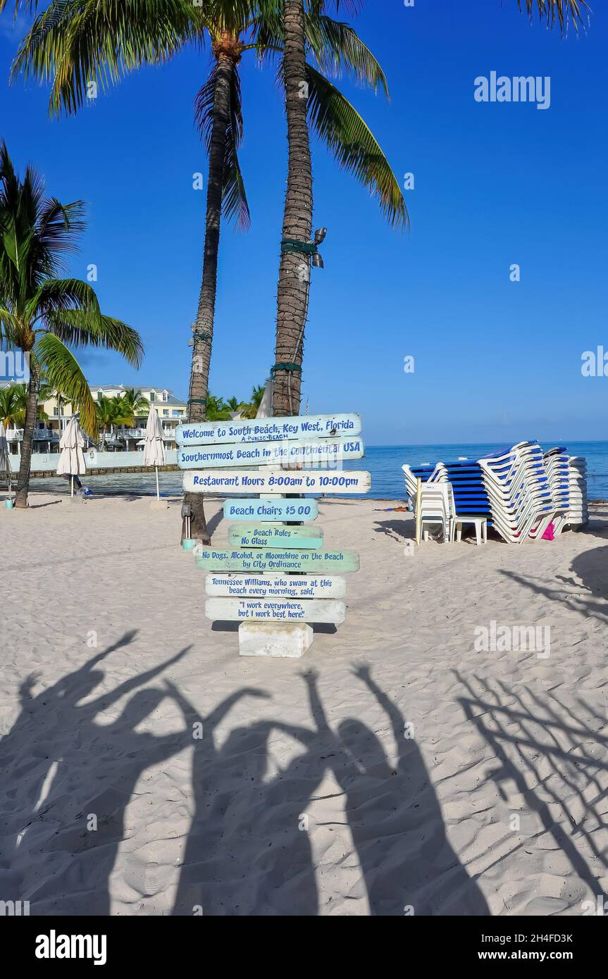 Schatten-Selfie von Menschen, die am Strand des südlichsten Strandes von Key West, USA, mit Palmen und Meer bewaffnet sind: Menschen-Schatten reisen um die Welt Stockfoto