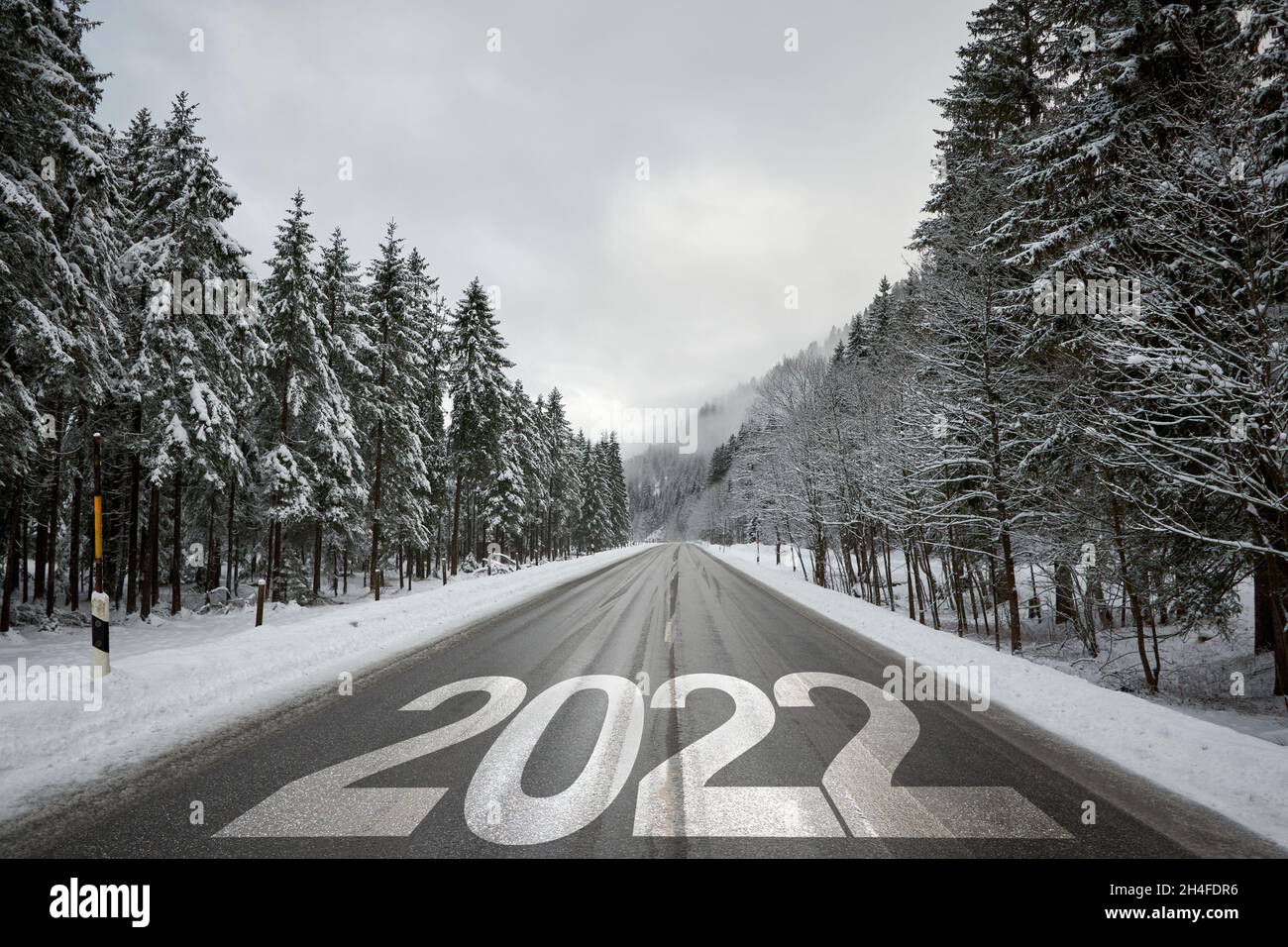 Nummer 2022 auf leerer offener Straße durch den Wald im Winter. Stockfoto
