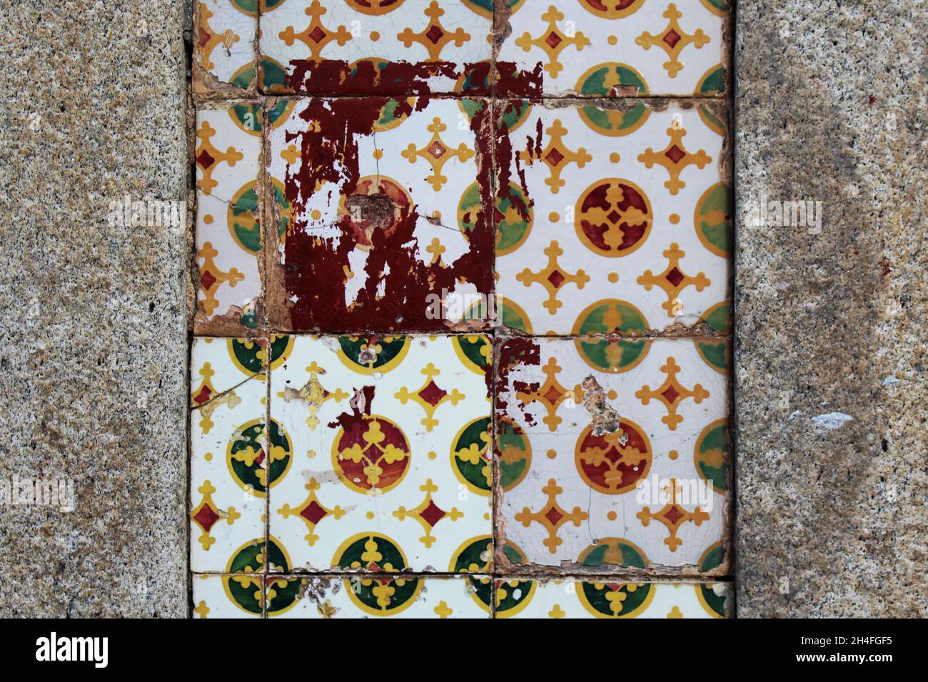 Alte, teilweise kaputte Fliesen in den Farben weiß grün rot und orange an einer grauen Hauswand in Espinho, Portugal. Stockfoto