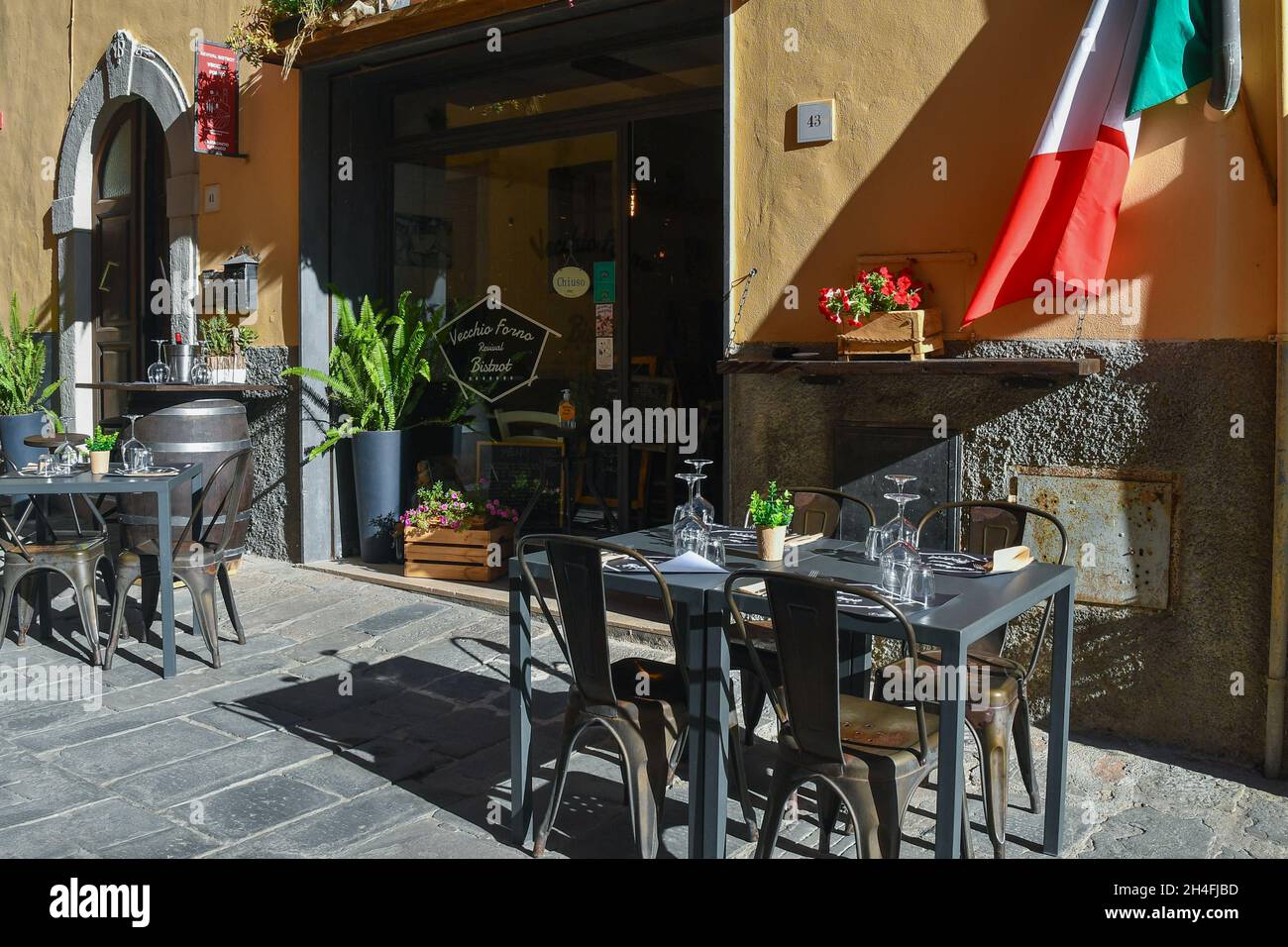 Tische und Stühle auf dem Bürgersteig vor einem typischen toskanischen Bistrot im mittelalterlichen Dorf Castagneto Carducci, Livorno, Toskana, Italien Stockfoto