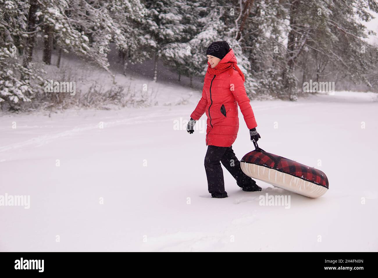 Mädchen in einer roten Jacke ziehen Schlauch in verschneiten Wald. Hohe Qualität Stockfoto