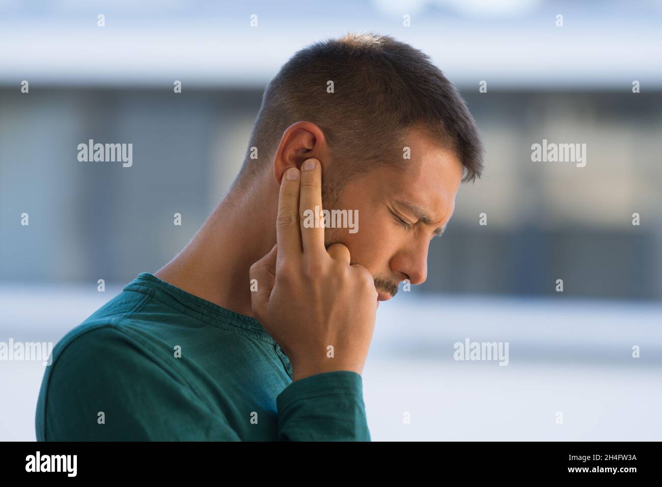 Mann mit Tinnitus. Mann, der sein Ohr wegen starker Ohrenschmerzen oder Ohrschmerzen berührt. Otitis Stockfoto