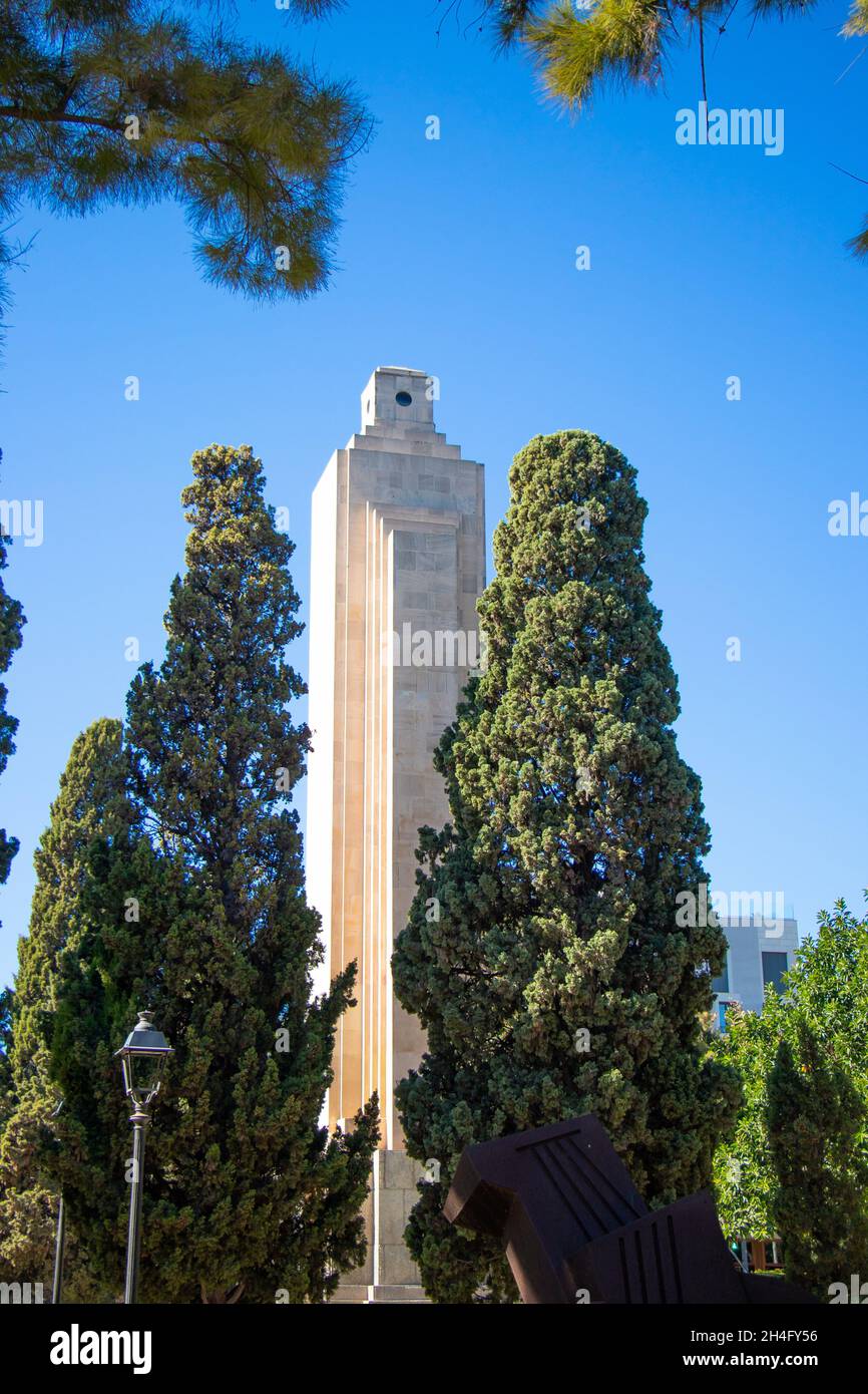 Hoher Turm durch üppige grüne Bäume unter einem klaren blauen Himmel in einem Stadtpark. palma Mallorca Stockfoto
