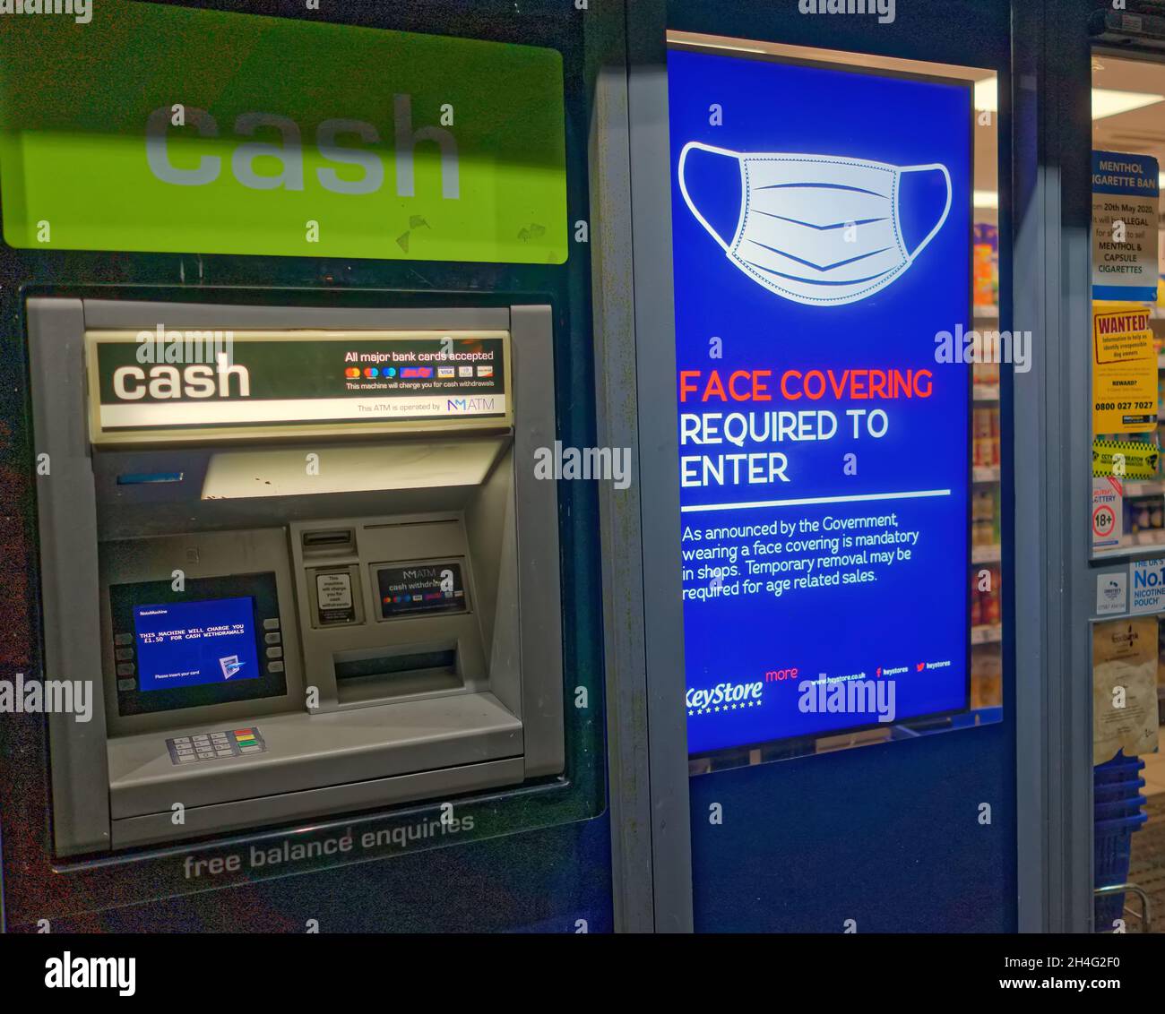 24-Stunden-Geschäft mit geldautomat vor dem Hotel, geldautomat, mit Maske auf der elektronischen Werbetafel neben dem Eingang der Eingangstür, die von der Bude entnommen wurde Stockfoto