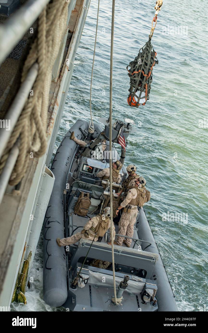 211026-M-ON629-1009 NAVAL SUPPORT ACTIVITY BAHRAIN (OKT 26, 2021) Marineinfanteristen, die dem Team der All Domain Reconnaissance Detachment Boat, 11. Marine Expeditionary Unit (MEU), zugewiesen wurden, übertragen simulierten Schmuggelware an Seeleute an Bord des amphibischen Dock-Landungsschiffes USS Pearl Harbor (LSD 52) während einer Bannerwiedergewinnungsübung bei der Naval Support Activity Bahrain, 26. Oktober. Pearl Harbor und das 11. MEU werden im Einsatzgebiet der 5. US-Flotte eingesetzt, um Marineinteraktionen zu unterstützen, um die maritime Stabilität und Sicherheit in der Zentralregion zu gewährleisten und den Mittelmeerraum und den Pazifik über das W zu verbinden Stockfoto