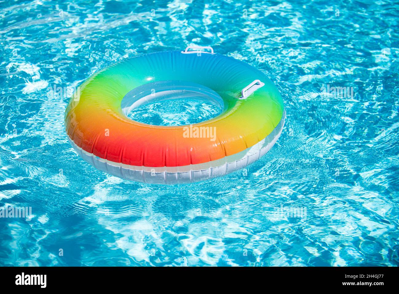 Aufblasbarer Gummiring, der in einem blauen Pool schwimmt. Stockfoto