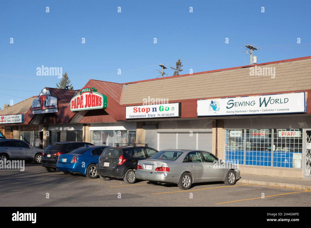 Geschäfte für kleine Unternehmen in einem Einkaufszentrum mit Näherei, Supermarkt, Pizzeria und Restaurant. Stockfoto