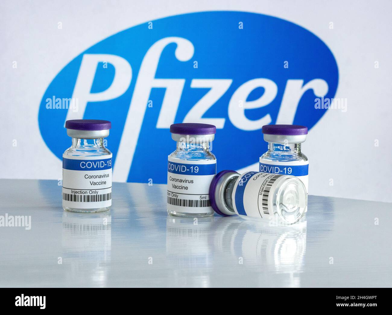 Fläschchen mit Coronavirus-Impfstoff mit dem Pfizer-Logo im Hintergrund Stockfoto