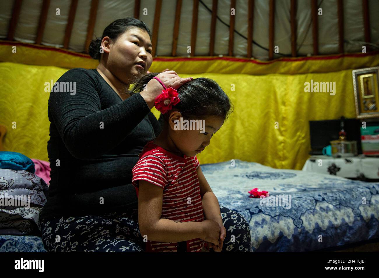 Pagmadulam, 33, bindet die Haare ihrer Tochter Khngorzul, 4, in ihrem Haus, als sich die Nacht in einem Ger-Bezirk der Hauptstadt Ulaanbaatar nähert, Januar 19 Stockfoto