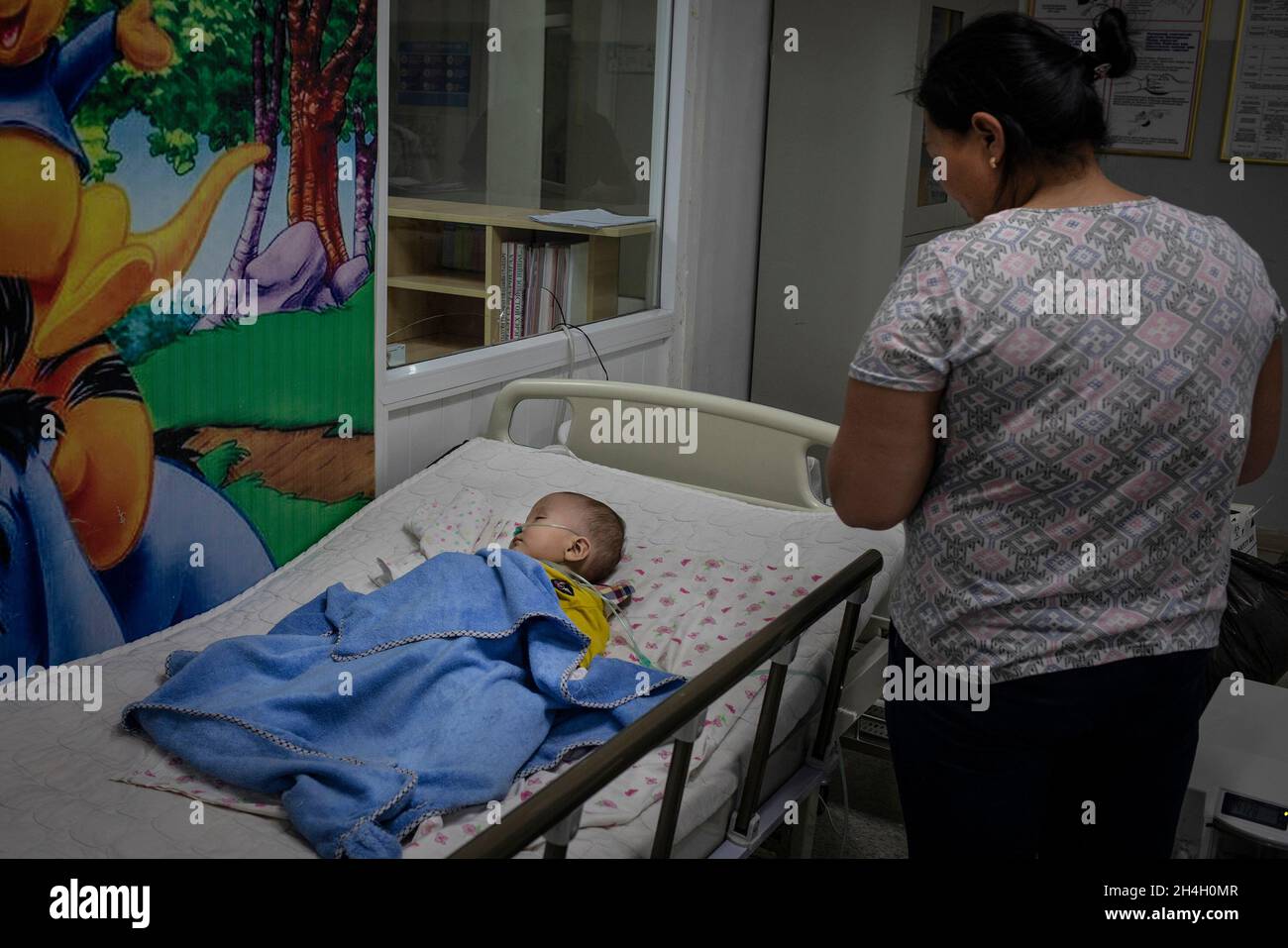 Eine Mutter schaut in einer Kindernotaufnahme in einem der städtischen Krankenhäuser in der Hauptstadt auf ihren kleinen Jungen, der an Atemwegserkrankungen leidet Stockfoto