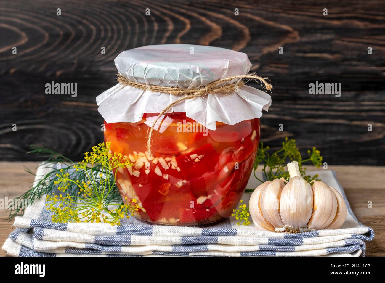 Hausgemachte eingelegte rote Paprika in Gläsern auf Holzregal hausgemachte Konserven und fermentierte Lebensmittel Konzept Saisonprodukt. Stockfoto