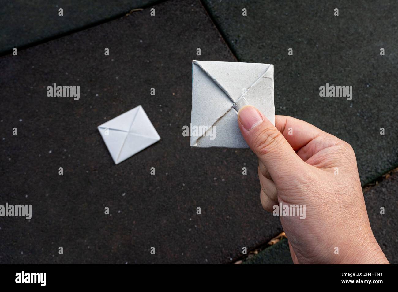 Eine Hand, die ein Papier-Ttakji auf einem Spielplatz hält Stockfoto