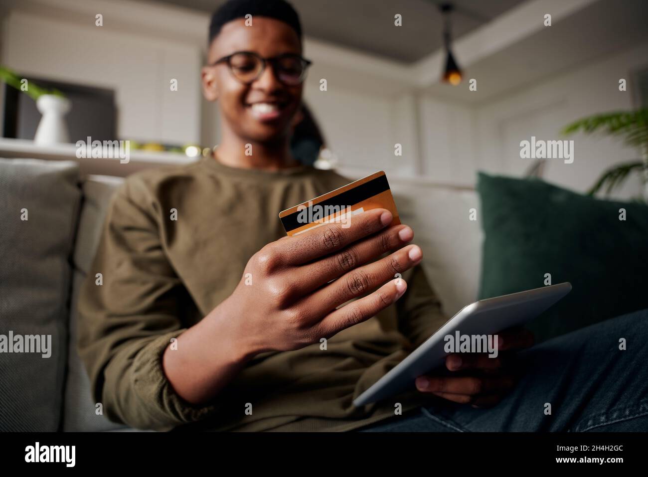 Junger Erwachsener schwarzer Mann macht online Kauf auf Sofa entspannt und glücklich Stockfoto