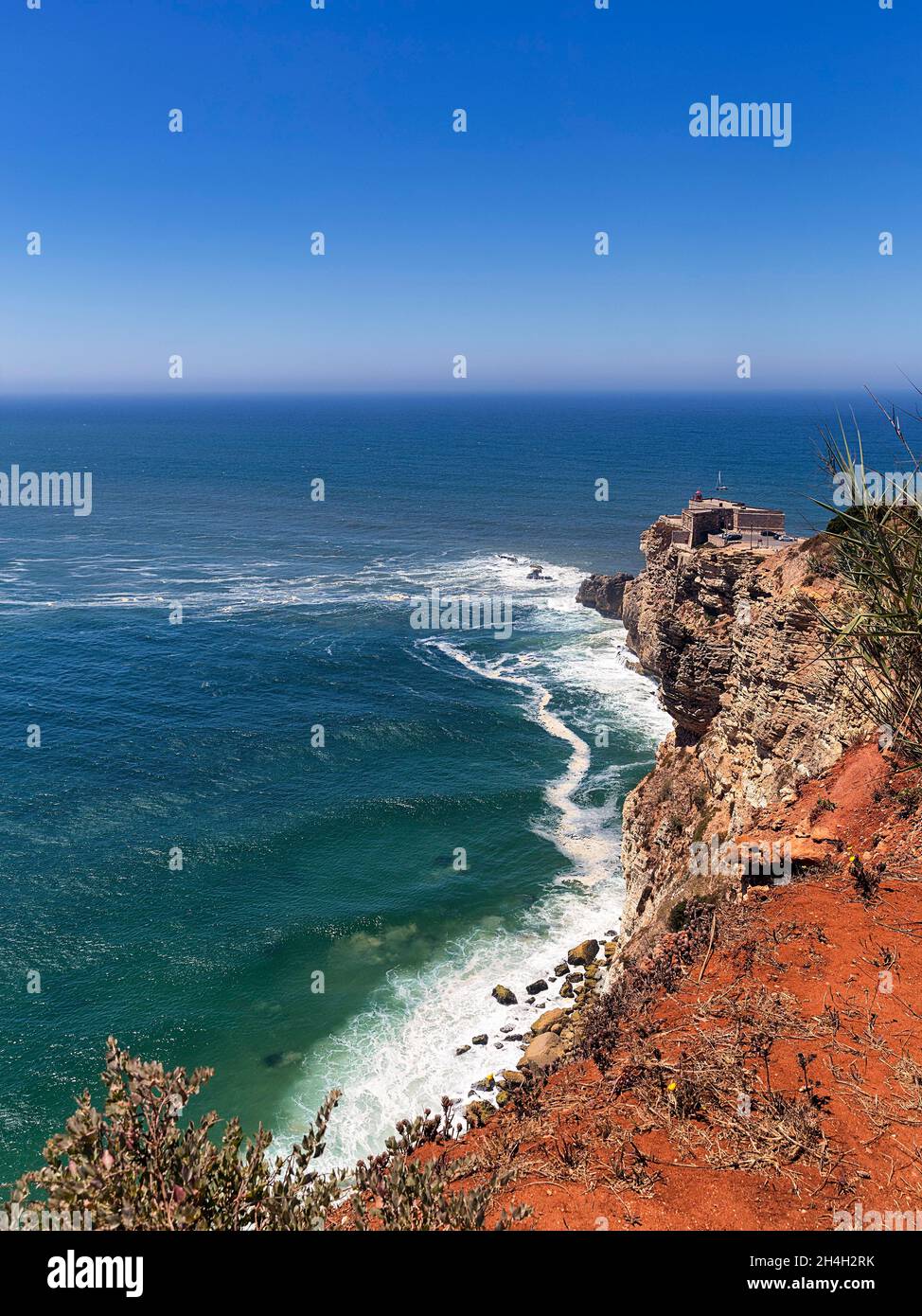 Blick entlang der Klippen auf den Leuchtturm Farol de Nazare und den Atlantischen Ozean, Praia do Norte, Nazare, Portugal Stockfoto