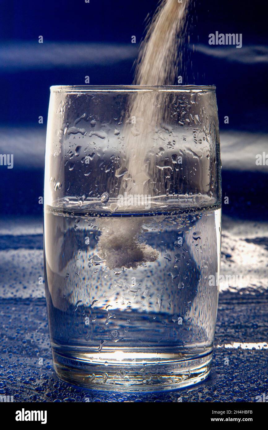 In Pulverform Medizin in ein Wasserglas gießen Stockfoto