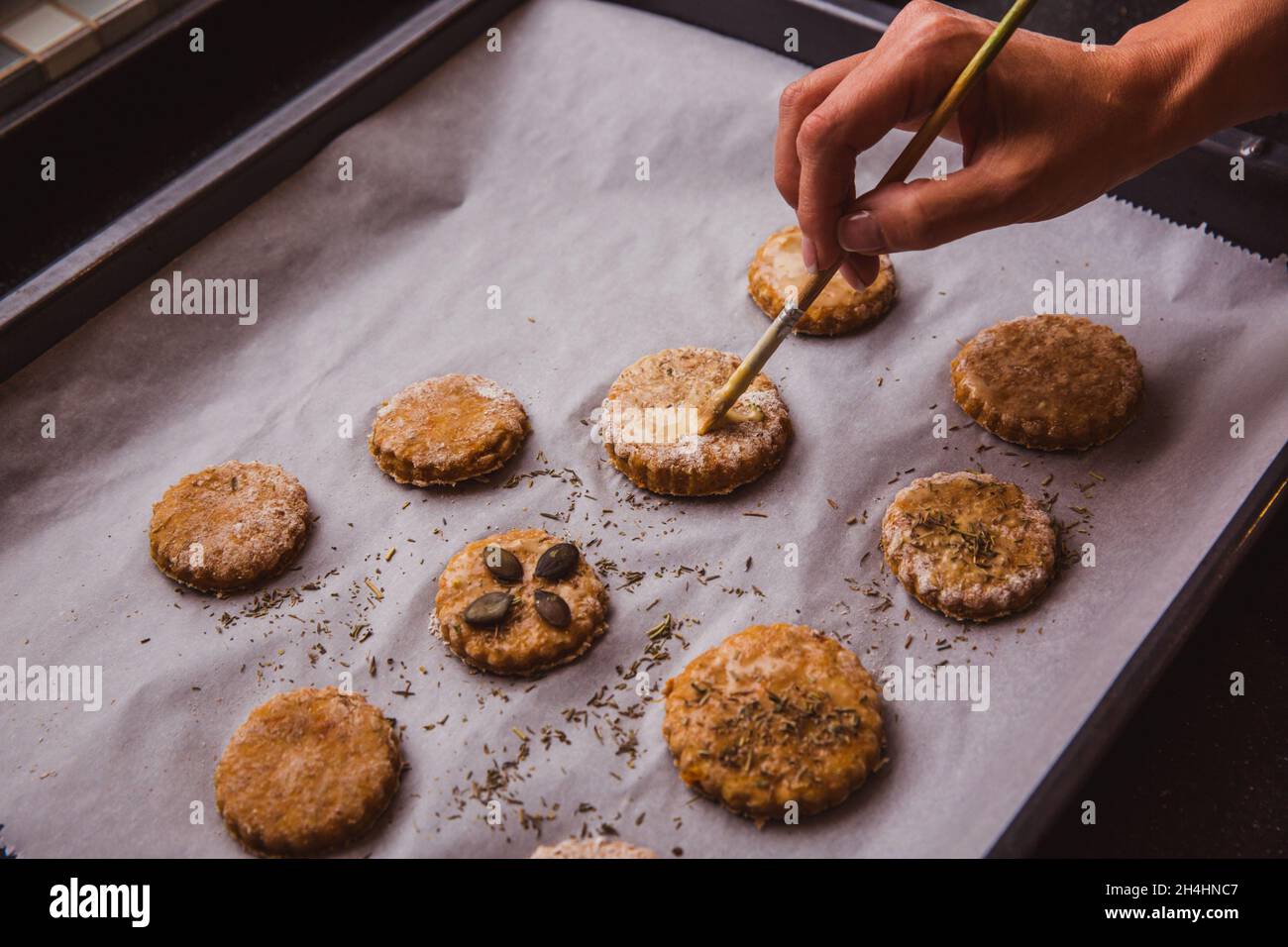 Frau glasieren Scones mit Bürste bereit, in den Ofen zu gehen. Nahaufnahme Stockfoto