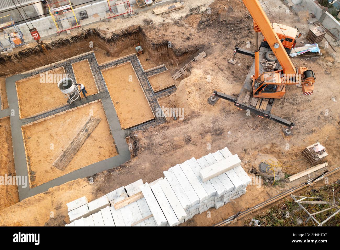 Gründung eines zukünftigen Hauses. Gießfundament mit Zement auf Baustelle mit Kran, Luftaufnahme. Stockfoto
