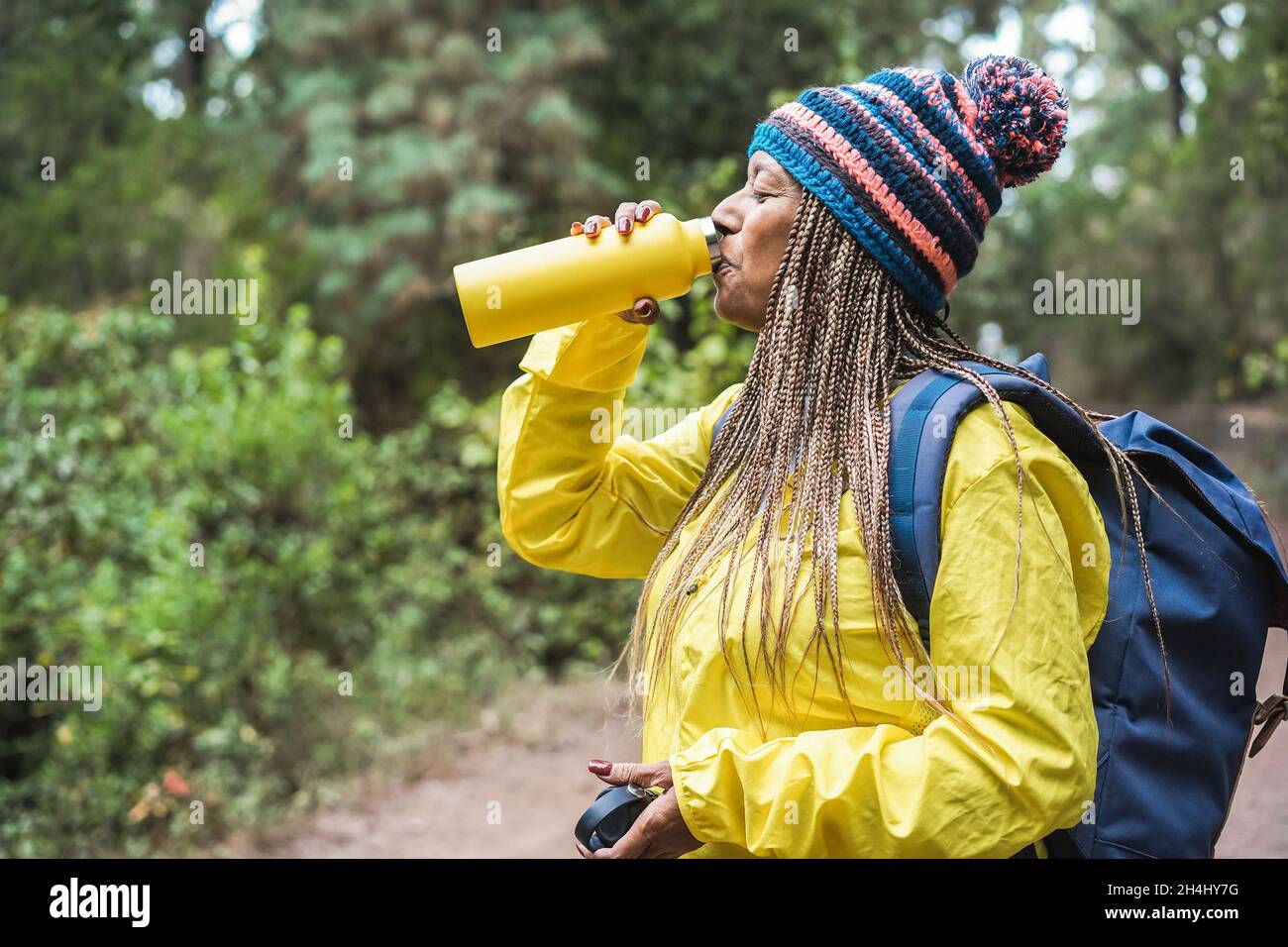 Ältere afrikanerin trinkt während des Trekkingtages in den Wald - Fokus auf Gesicht Stockfoto