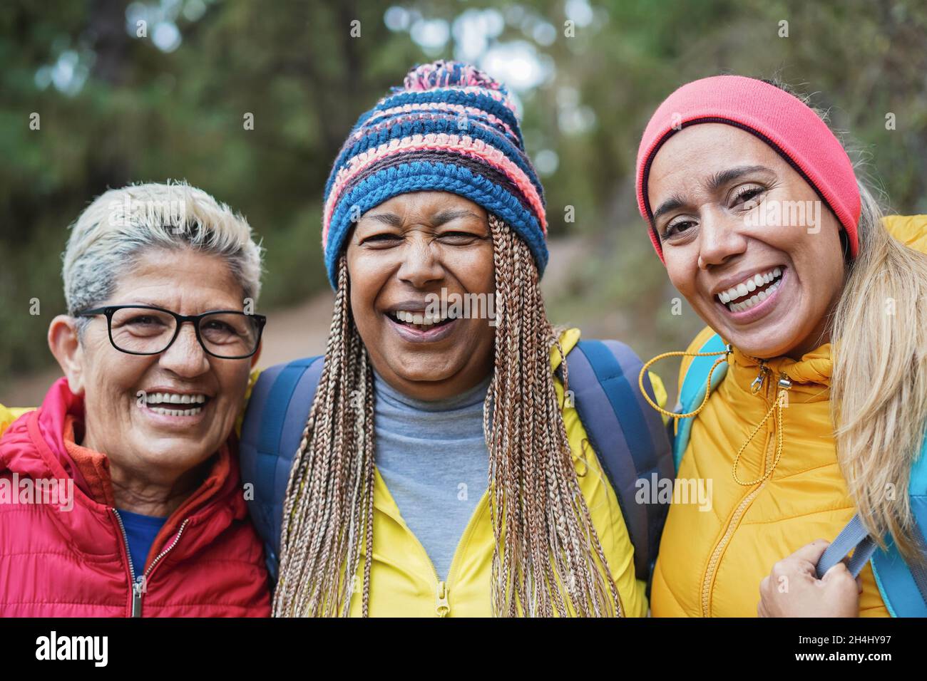 Portrait von multirassischen älteren Freunden, die sich während des Trekkingtages in den Wald amüsieren - Fokus auf das rechte Frauengesicht Stockfoto