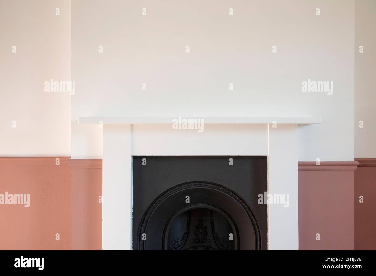 Viktorianischer Holzkamin, umgeben von weißen und rosafarbenen Wänden Stockfoto