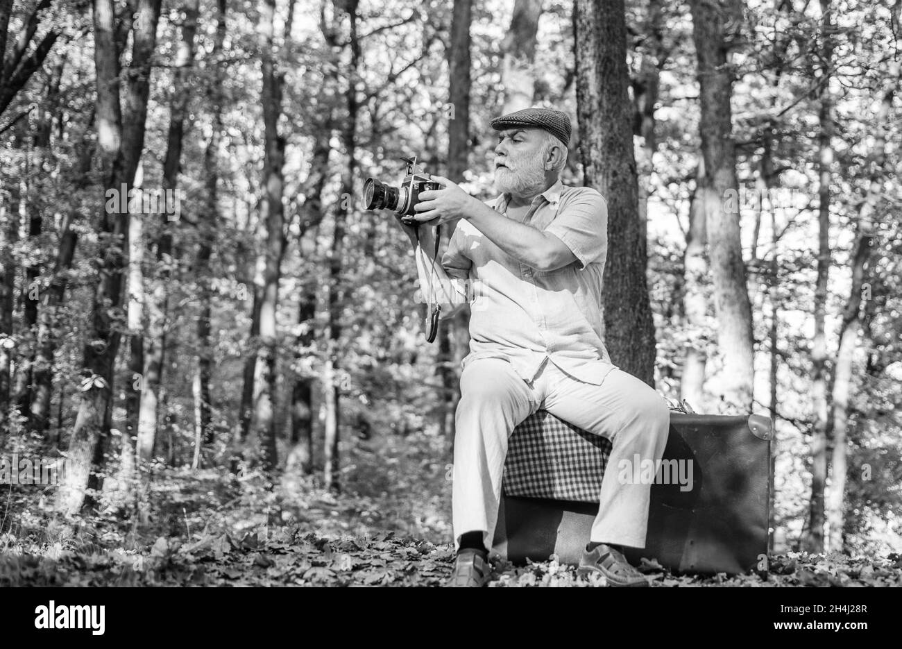 Kameramann im Freien. Professioneller Fotograf. Pension Hobby. Retro-Fotograf. Wird für manuelle Einstellungen verwendet. Alter Mann schießt in der Natur. Landschaft und Stockfoto