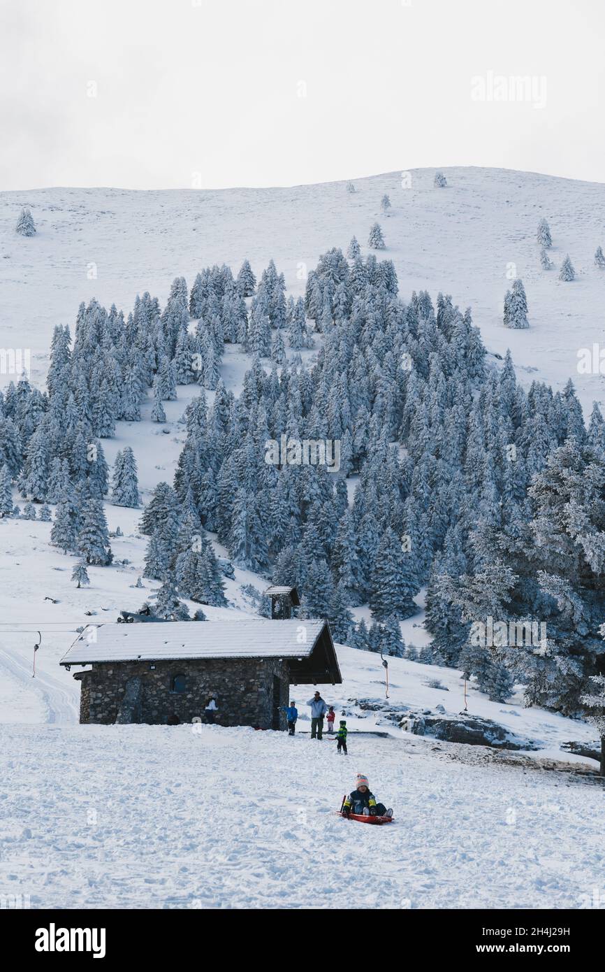 Kalavryta Skigebiet, Griechenland - Dezember, 31 2019: Glückliche Kinder mit Vater genießen Winterurlaub im Skigebiet in Griechenland. Kinder haben Spaß im Freien Stockfoto