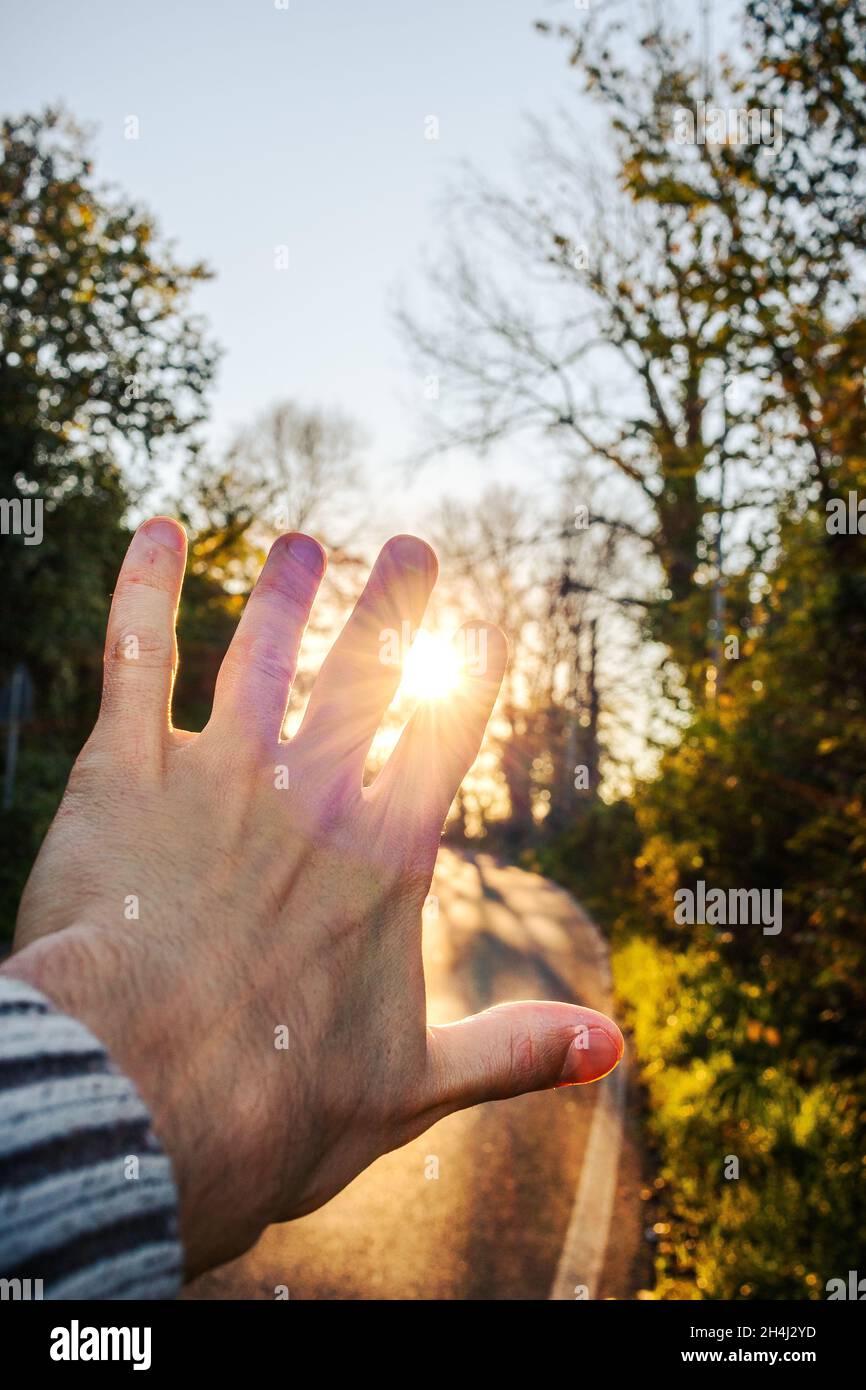 Mann Hand angehoben in Richtung Sonnenuntergang. Reisen Sie auf der Straße Stockfoto