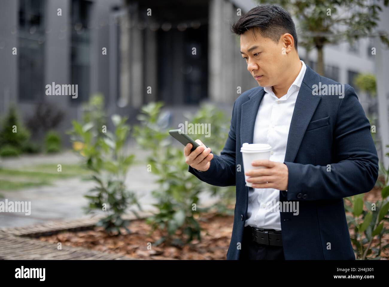 Geschäftsmann mit Kaffeetasse, die auf dem Smartphone anruft Stockfoto