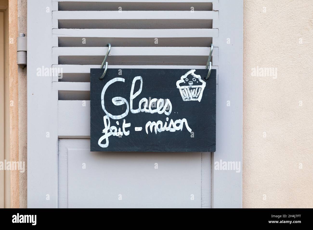 Nahaufnahme eines Schiefer-Schreibens, der an einem Fensterladen befestigt ist und auf Französisch sagt: Glaces fait maison - was auf Englisch bedeutet - hausgemachtes Eis. Stockfoto