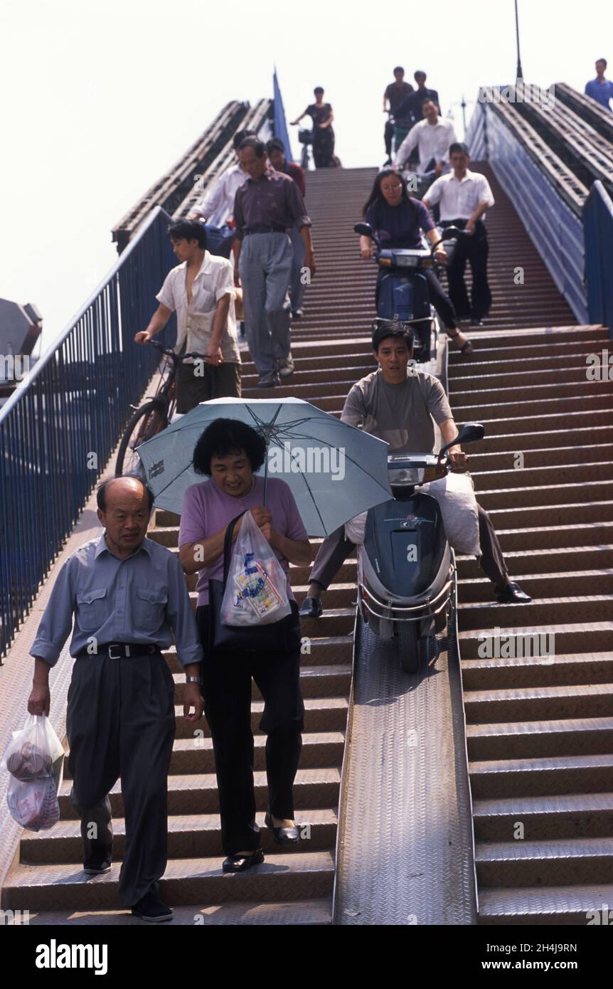 Hangzhou, Provinz Zhejiang, China. 2000er Jahre, 2001. Junge moderne chinesische Männer und Frauen fahren auf ihren Motorrädern eine zentral gelegene Fahrradrampe mitten in einer Fußgängerbrücke hinunter. HOMER SYKES Stockfoto