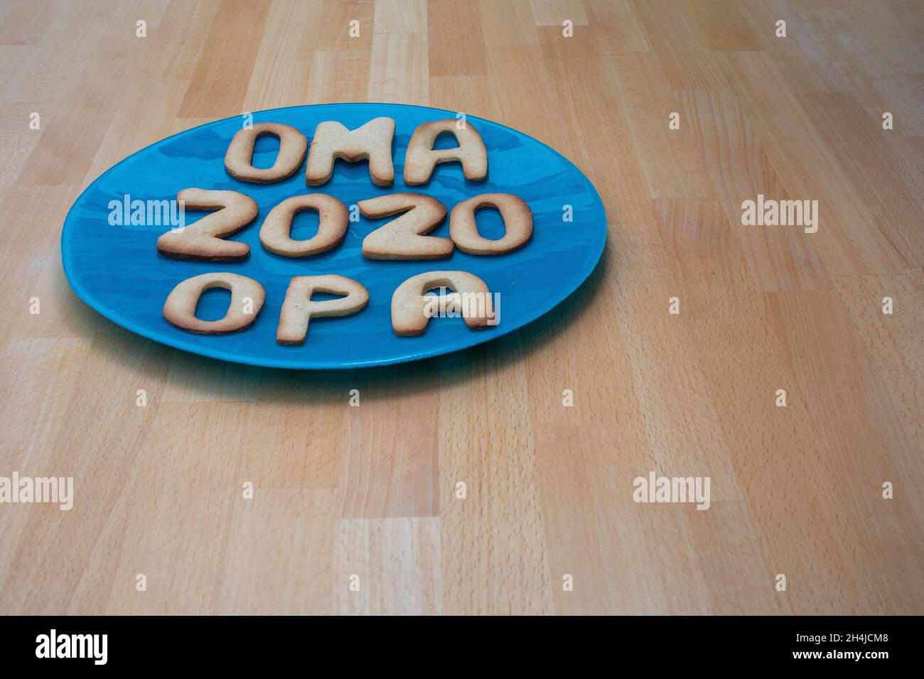 Kekse auf einem blauen Teller auf einem Holztisch mit den deutschen Worten für Oma und Opa und das Jahr 2020 Stockfoto