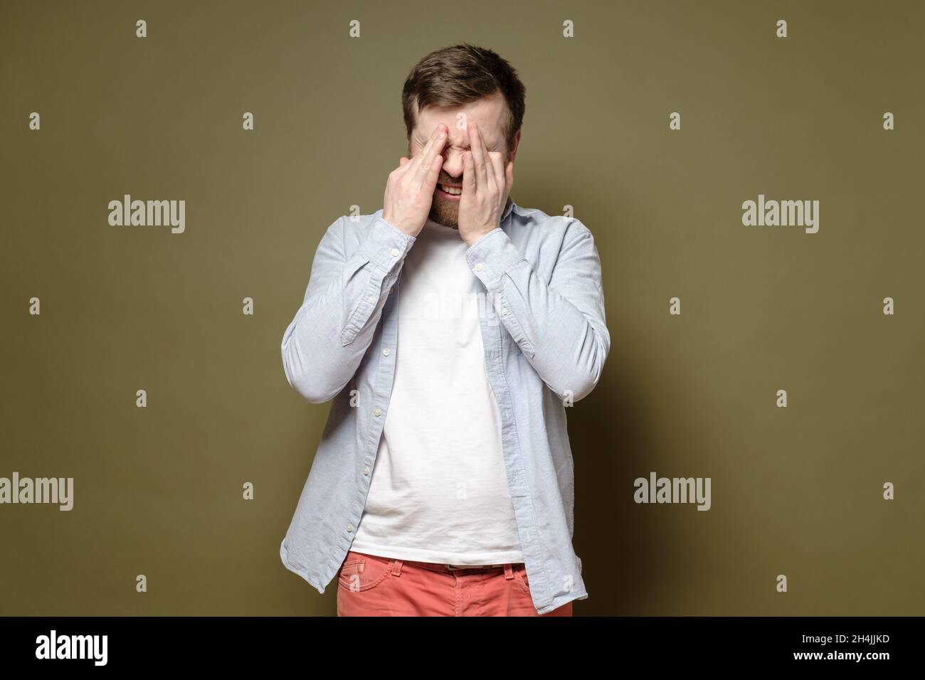 Der Mensch ist deprimiert, er ist unglücklich und schluchzt und wischt mit den Händen die Tränen aus den Augen. Psychologisches Gesundheitskonzept. Stockfoto