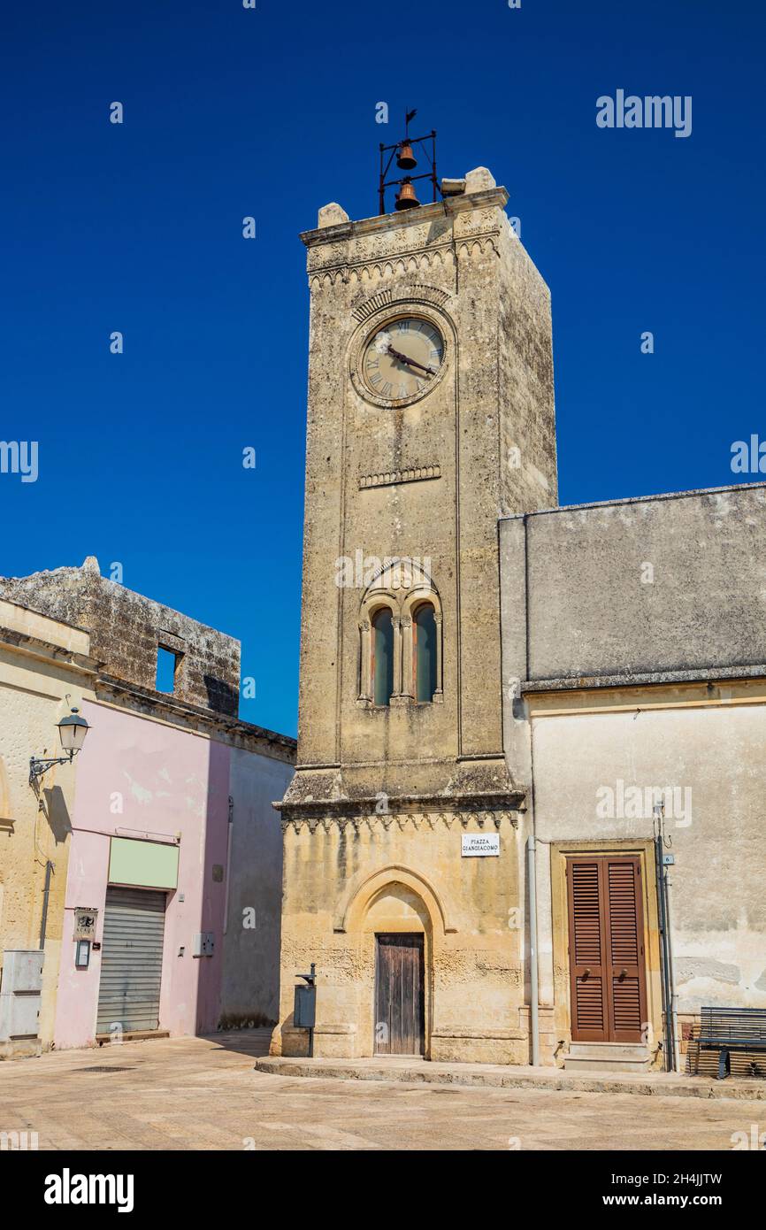 Das kleine Dorf Acaya, Lecce, Salento, Apulien, Italien. Der Turm mit der Uhr und dem Spulfenster. Der kleine Platz ist in flachem Stein gepflastert. Stockfoto