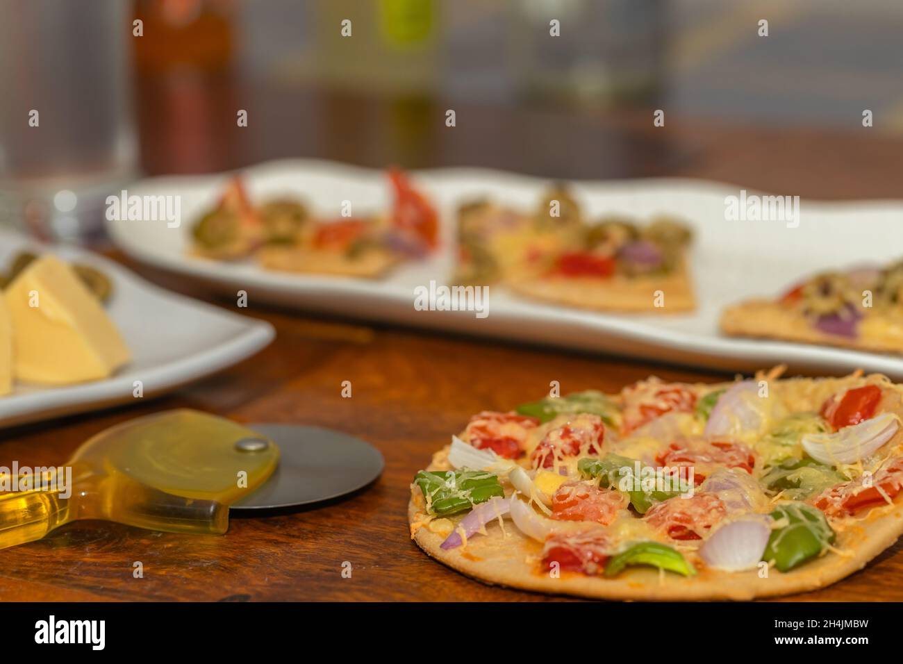 Seitenwinkel Selective Focus Bild von frisch gebackener und geschnittener Pizza zusammen mit den Zutaten, die auf dem Tisch serviert werden Stockfoto