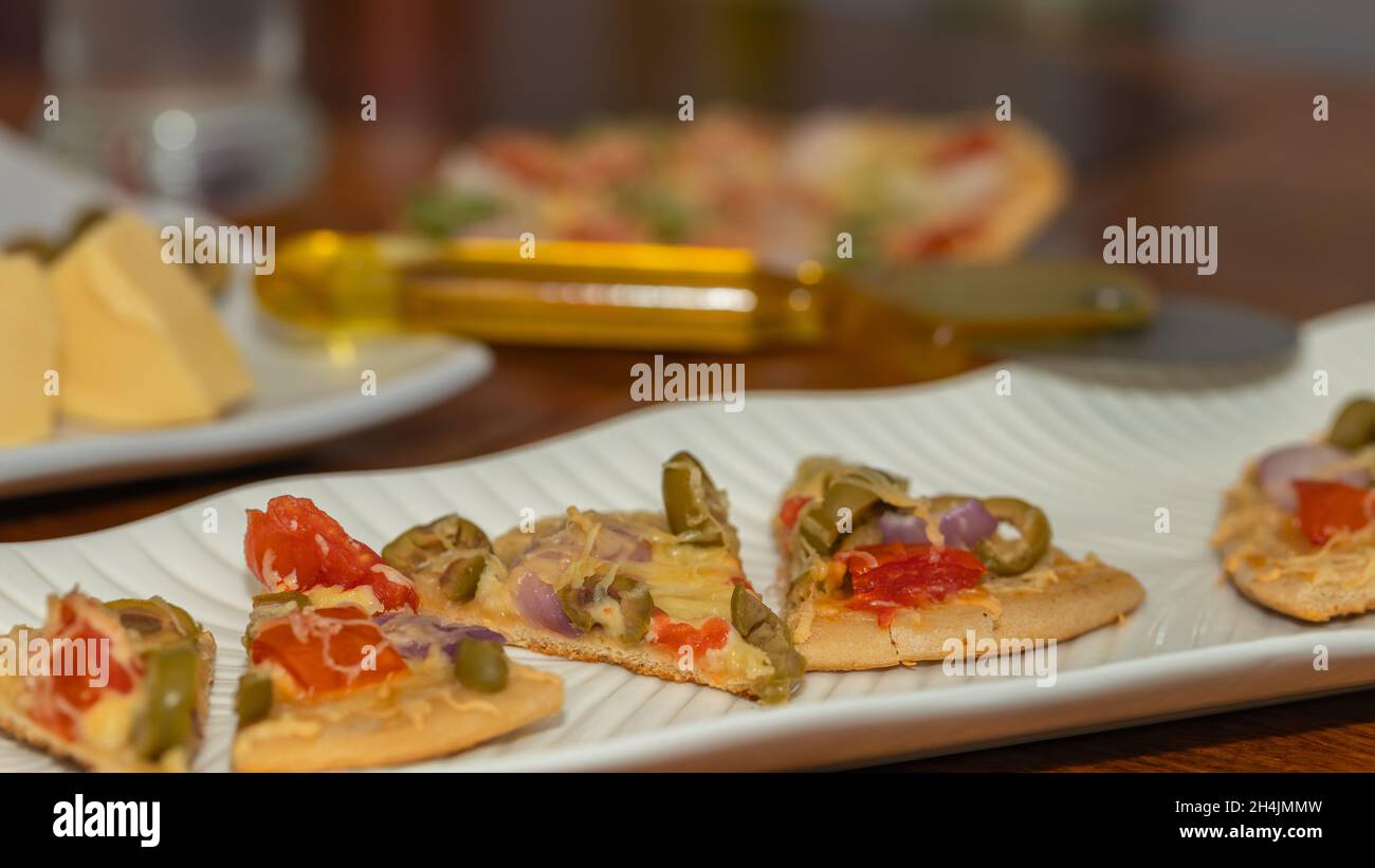 Seitenwinkel Selective Focus Bild von frisch gebackener und geschnittener Pizza zusammen mit den Zutaten, die auf dem Tisch serviert werden Stockfoto