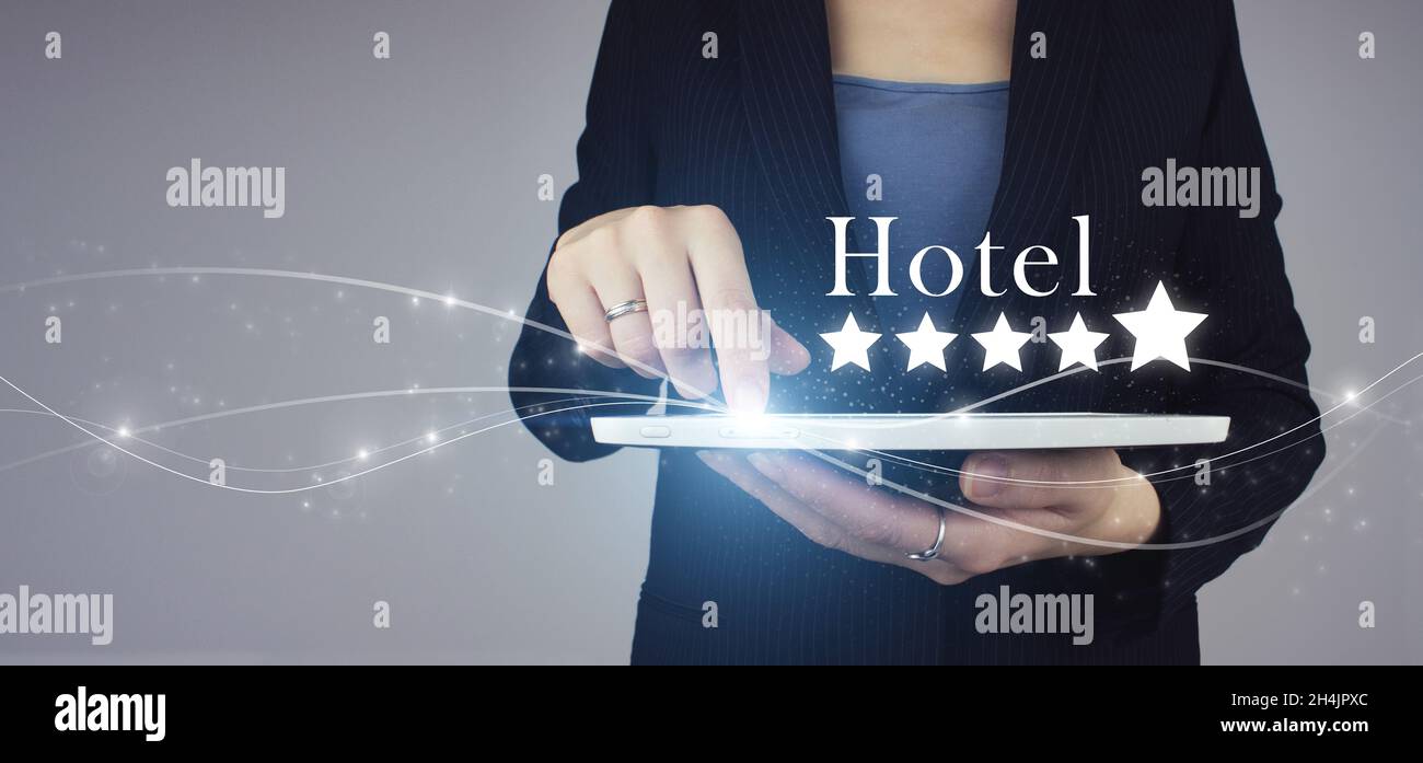 Customer Experience Konzept. Weißes Tablet in Geschäftsfrau Hand mit digitalem Hologramm fünf Sterne und Text Hotel auf grauem Hintergrund. Kundenerfahrung Stockfoto