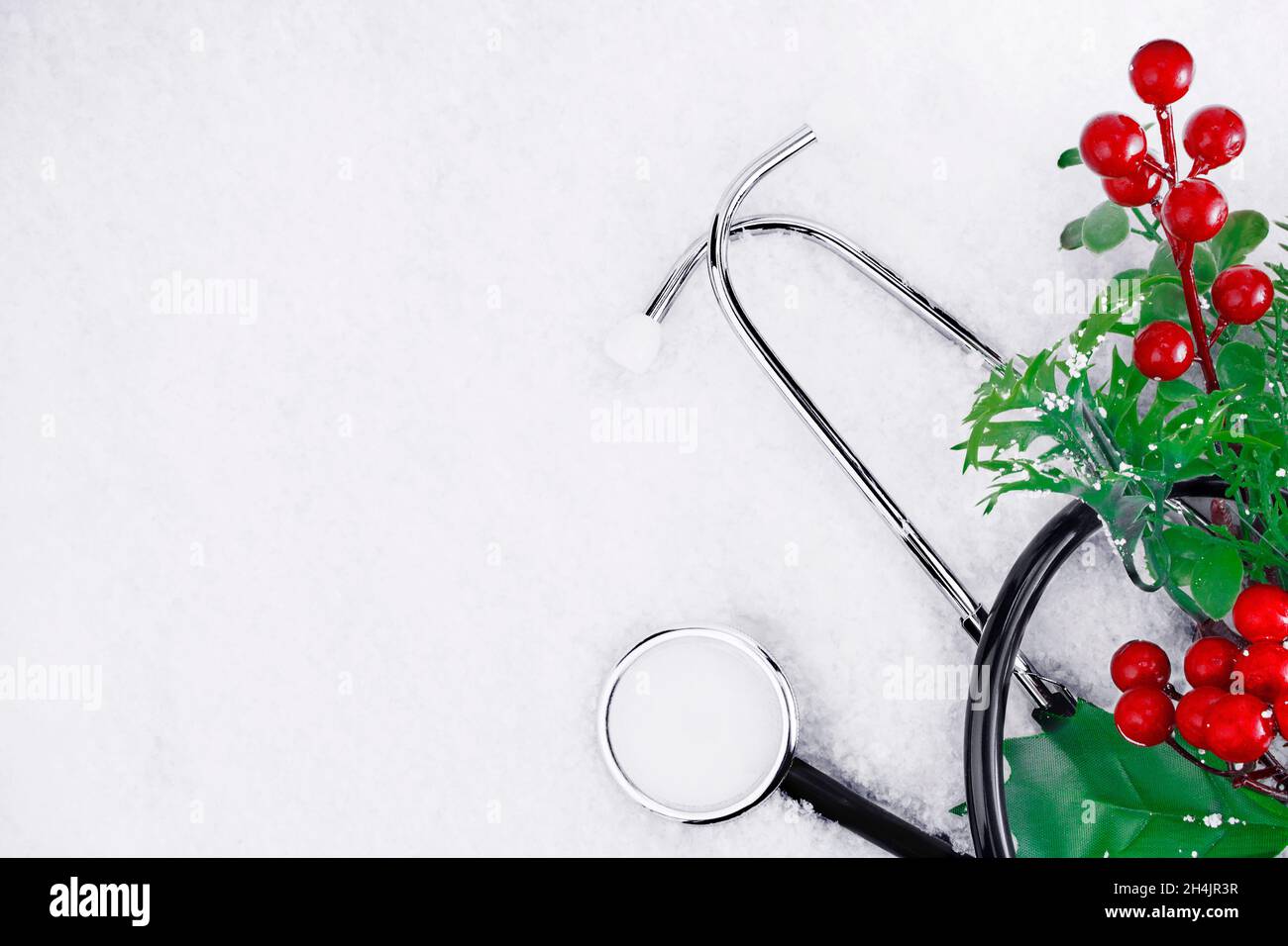 Medizinisches Stethoskop auf einem verschneiten Hintergrund in der Nähe eines Weihnachtszweiges. Medizinisches Konzept für Weihnachten oder Neujahr. Flach. Speicherplatz kopieren Stockfoto