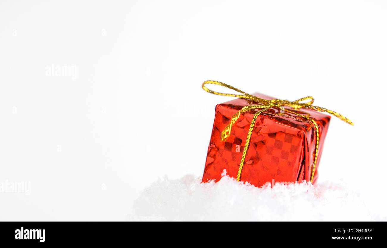Geschenk in roter Verpackung auf dem Schnee. Selektiver Fokus. Konzept für weihnachten oder Neujahr, Geschenke, weihnachtseinkäufe oder -Verkäufe. Banner. Speicherplatz kopieren Stockfoto