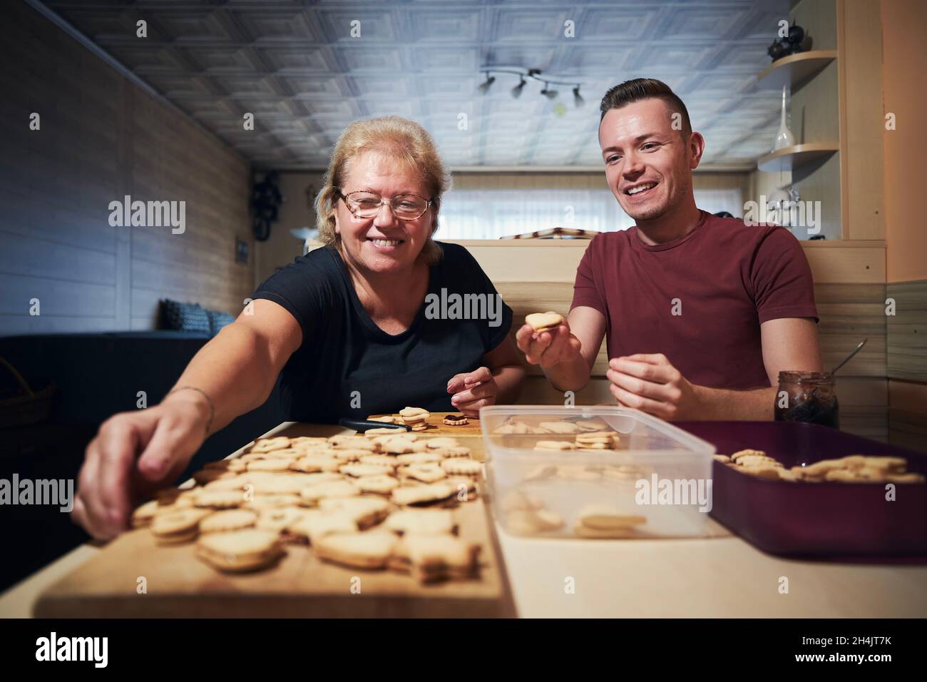 Junger erwachsener Mann, der seiner Mutter beim Backen von Weihnachtsbonbons in der heimischen Küche hilft. Tradition während des Advents in Tschechien. Stockfoto