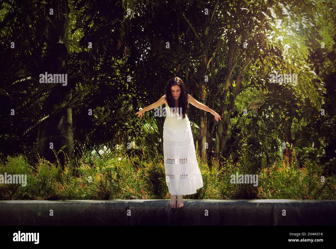 Frau in einem weißen Kleid, die gerade von einer Wand springen wird Stockfoto