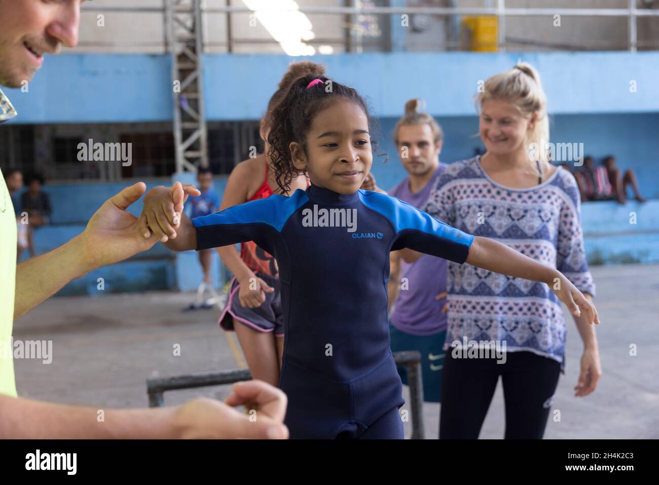 Brasilien, Rio de Janeiro, Favela Babilonia, auf Initiative des Maewan-Vereins und der lokalen Verbände Favelasonha und Mawon während einer Kooperation zur Förderung des Sports in den Favelas, den beiden Highlinern Antony Newton und Pablo Signoret, mehreren Highline-Weltmeistern, Eine Initiation Slackline in der Favela-Turnhalle installiert haben, unternimmt Eloise, 8 Jahre alt, immer noch in einem Neoprenanzug, ihre ersten Schritte auf der Slackline, Das Gymnasium ist der privilegierte Ort des Lebens für diese Kinder, die aufgrund der COVID-Krise seit 2 Jahren nicht mehr zur Schule gehen konnten Stockfoto