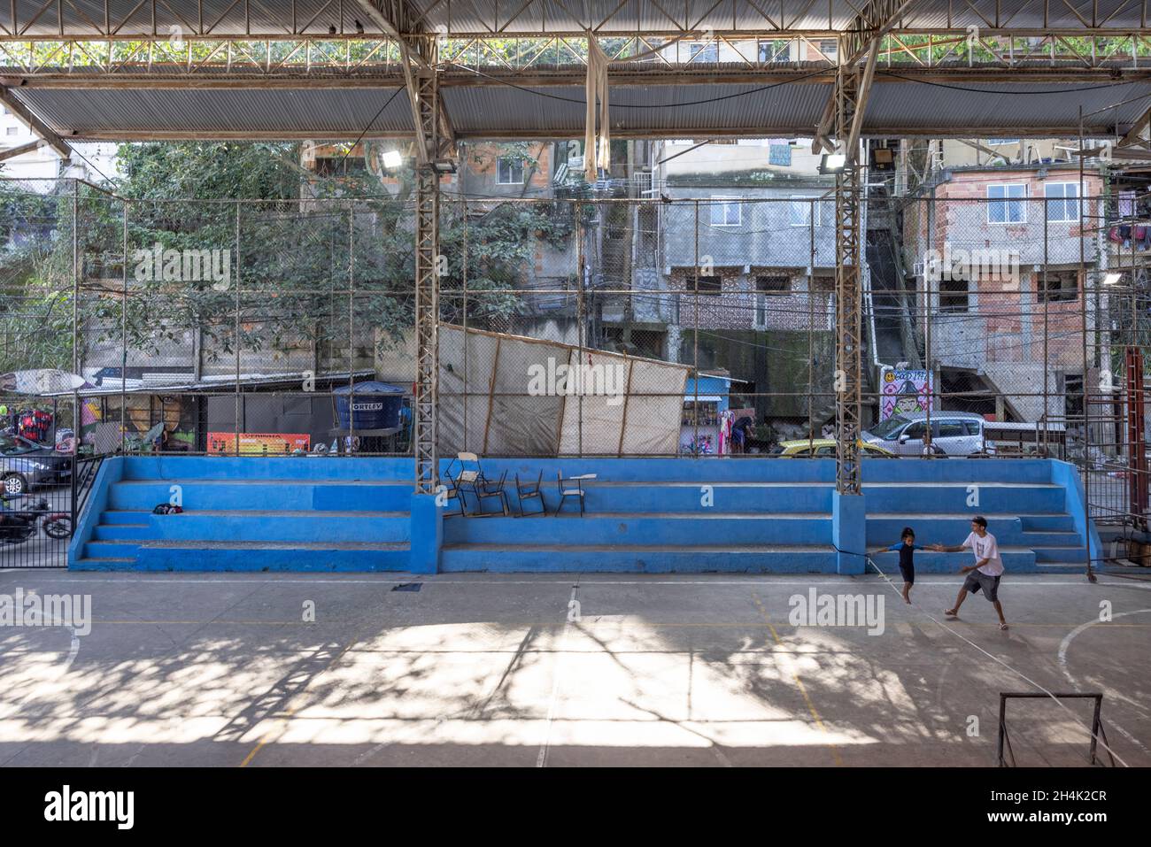 Brasilien, Rio de Janeiro, Favela Babilona, auf Initiative des Maewan-Vereins und der lokalen Verbände Favelasonha und Mawon während einer Zusammenarbeit zur Förderung des Sports in den Favelas, den beiden Highlinern Antony Newton und Pablo Signoret, mehrere Highline-Weltmeister, Eine Initiation Slackline in der Favela-Turnhalle installiert haben, unternimmt Eloise, 8 Jahre alt, noch in einem Neoprenanzug, ihre ersten Schritte auf der Slackline mit Valdemir, Das Gymnasium ist der privilegierte Ort des Lebens für diese Kinder, die aufgrund der COVID-Krise seit 2 Jahren nicht mehr zur Schule gehen konnten Stockfoto