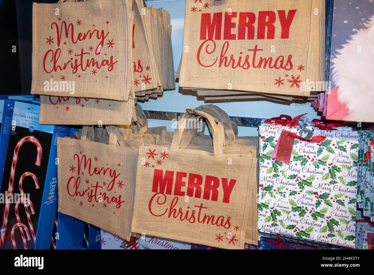 Canvas-Einkaufstaschen mit fröhlichen Weihnachten auf einer roten Tasche, die in einem Supermarkt in Norfolk England an einer Wand hängt Stockfoto
